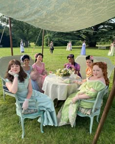 a group of women sitting around a table under a tent