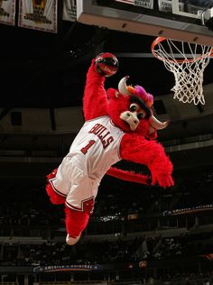 the mascot is jumping up into the air to dunk the basketball in front of him