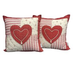 two red pillows with hearts on them sitting next to each other in front of a white background