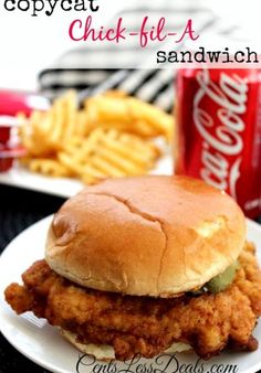 a chicken sandwich on a white plate next to some french fries and a can of coke