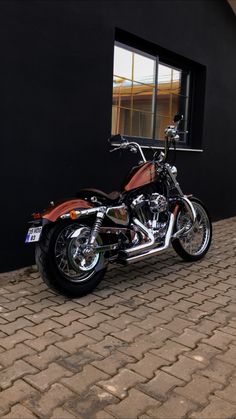 a red motorcycle parked in front of a black building with a window on the side