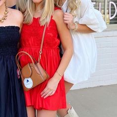 three women standing next to each other in front of a building