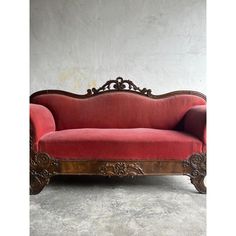 a red couch sitting on top of a cement floor