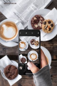 a person holding up a cell phone to take a photo of desserts and coffee