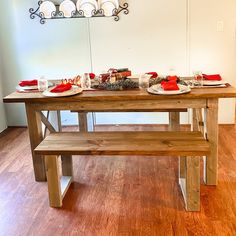 a wooden table with plates and cups on it, next to a bench in a room