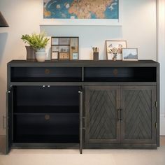 a black cabinet with drawers and pictures on the wall