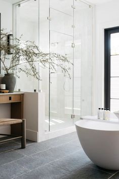 a white bath tub sitting next to a bathroom sink under a mirror on top of a wooden cabinet