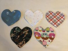 four heart shaped bibs are laid out on a white surface with different patterns and designs