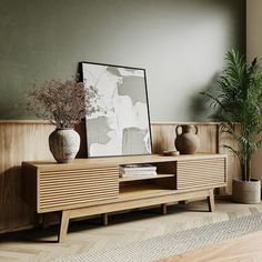 a wooden entertainment center with vases and plants on it's sideboard in a living room