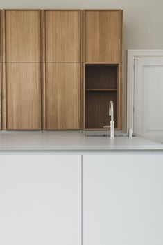 an empty kitchen with white counter tops and wooden cabinets