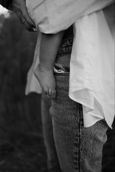 a black and white photo of a person holding a child's hand