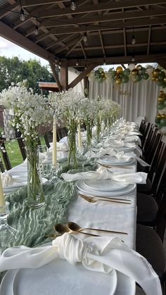 a long table is set with white flowers and place settings for the guests to sit down