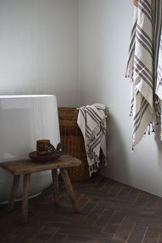 a towel hanging on the wall next to a bathtub and wooden stool in a bathroom