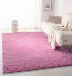 a living room with a white couch and pink rugs on the floor in front of a window