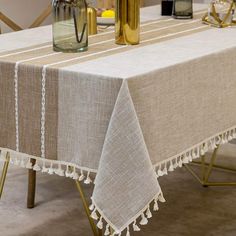 a table with two vases on top of it next to a white table cloth