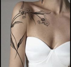 a woman wearing a white dress with flowers on her arm and chest tattooing it's upper half