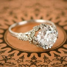 a diamond ring sitting on top of a brown and white patterned table cloth with an intricate design