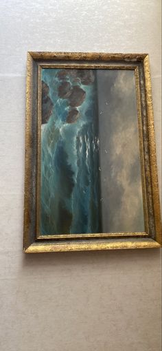 a painting hanging on the side of a wall next to a white wall with a gold frame