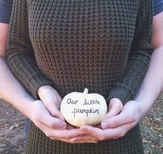 a woman is holding a pumpkin in her hands with writing on it that says our little pumpkin