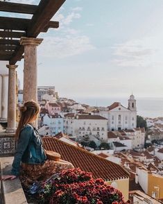 a woman sitting on top of a building next to a planter filled with flowers