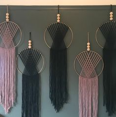 three black and pink wall hangings with wooden bead accents on the top one