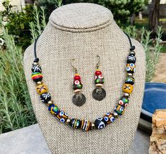 A variety of colorful African Krobo beads are interspersed with brass spacers and stringed on leather. Double-sided brass scarab charms dangle from matching earrings. Length of earrings: 1.75 inches. Multicolor Brass Jewelry With Dangling Beads, Handmade Multicolor Brass Beaded Necklaces, Handmade Multicolor Brass Beaded Necklace, Multicolor Brass Beaded Necklaces As Gift, Multicolor Round Beaded Brass Jewelry, Multicolor Dangle Jewelry With Wooden Beads, Eclectic Wooden Beads Jewelry Gift, Adjustable Eclectic Jewelry With Wooden Beads, Eclectic Adjustable Jewelry With Wooden Beads