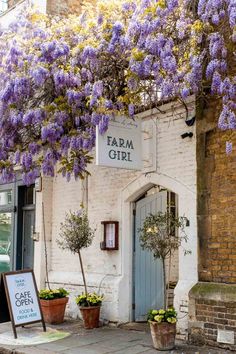 a building with purple flowers growing on it's side and a sign that says farm girl