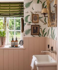 a bath room with a sink a window and some pictures on the wall next to it