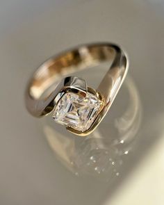 an engagement ring with a diamond in the center on a white surface, close up