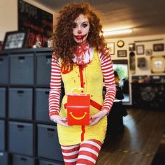 a woman dressed as a clown holding a box