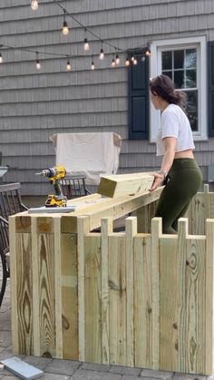 a woman is working on a wooden fence with a driller and screwdriver