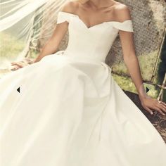 a woman in a white wedding dress sitting on a bench with her hand on her knee