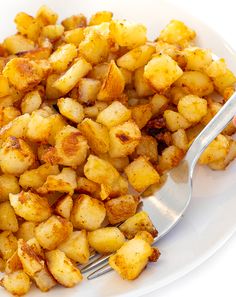 a white plate topped with fried potatoes and a fork