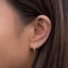 a woman's ear is shown with two small diamond hoops on the side