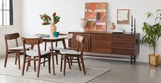 a dining room table and chairs in front of a large window with potted plants