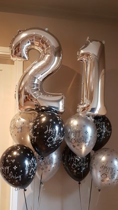 the number twenty five balloons are hanging on the wall with black and silver balloons in front of it