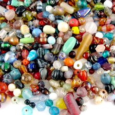 many different colored glass beads on a white surface