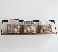 three wicker baskets are sitting on a shelf with books and magazines in front of them