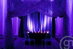 a table with candles on it in front of purple curtains