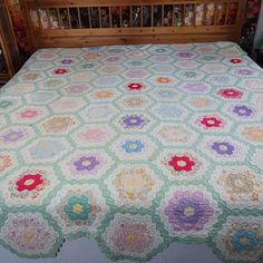 a bed with a quilt on top of it in front of a wooden headboard