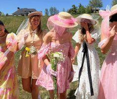 four girls in dresses and hats are posing for the camera with one girl holding flowers