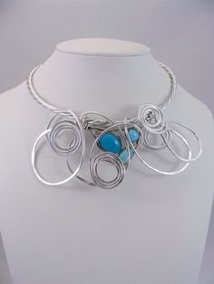 Bib silver statement necklace.Unique original design .Focal pendant has three colours of blue and two clear rhinestones. Created freehand by twisting and hammering the wire into a Funky Design. Adjust the neckwire to the shape of your neck. Aluminum is lightweight,easy to wear and will not oxidize. Aluminum is hypoallergenic. Modern Silver Pendant Jewelry, Modern Twist Silver Wire Wrapped Jewelry, Modern Silver Wire Wrapped Necklace, Artistic Silver Wire Wrapped Necklaces, Artistic Silver Wire Wrapped Necklace, Silver Spiral Metal Necklaces, Silver Spiral Metal Necklace, Modern Twist Silver Metal Jewelry, Handmade Metal Jewelry With A Modern Twist