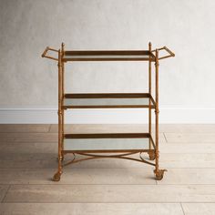 a gold metal and glass shelf with three shelves on each side, against a white wall