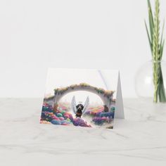 a greeting card with an angel in the middle and flowers around it on a marble surface