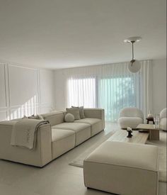 a modern living room with white furniture and large window curtains on the windowsills