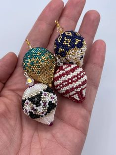 three beaded ornaments in the palm of someone's hand