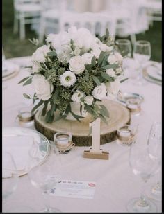 the table is set with white flowers and place settings for guests to sit down at