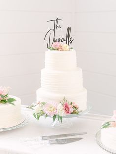 the wedding cake is white and has pink flowers on it, along with two other cakes