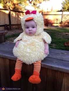 a baby in a chicken costume sitting on a bench