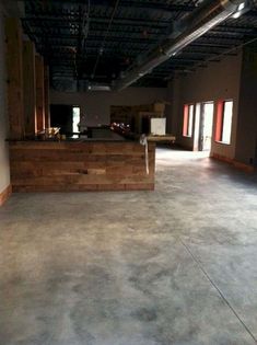 an empty room with concrete flooring and wooden counter tops in the center, surrounded by large windows